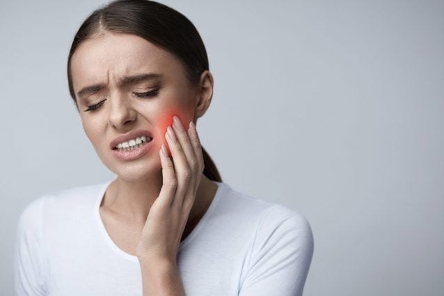 Woman with toothache holding her cheek, indicating pain or dental issue.