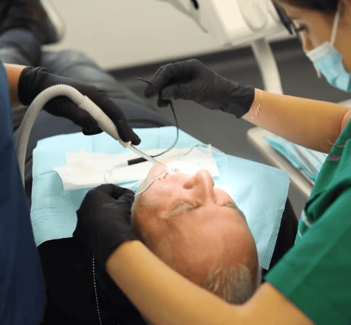 Patient receiving dental treatment in clinic, dentist using tools for oral care, close-up.
