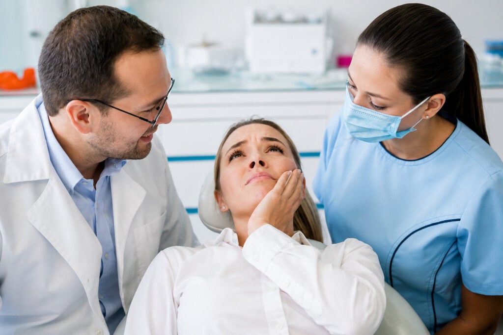 Radiografia dentale e modello di impianto mostrati da un dentista con guanti rosa, che illustrano la salute dentale e la procedura di impianto.
