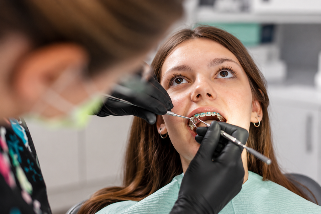 Smiling girl with braces sitting in a dental chair in an orthodontic clinic.